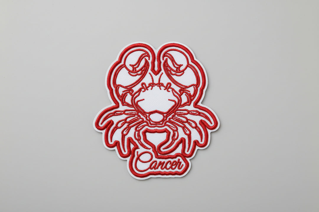 Red Cancer crab zodiac embroidered patch with “Cancer” script text on a white grid background.
