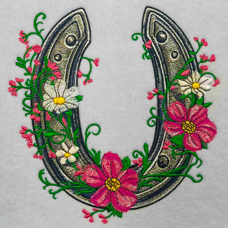 Embroidered design of a horseshoe with floral elements on a gray background