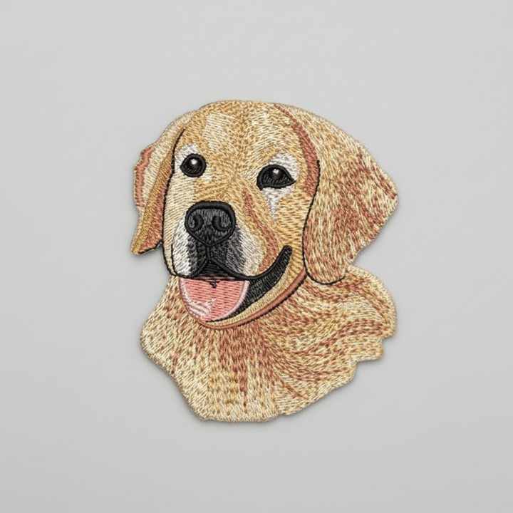 Realistic golden retriever embroidery patch featuring a friendly dog portrait with golden fur, floppy ears, black nose, and pink tongue, stitched with textured thread shading on a light background, original EmbroMania artwork.