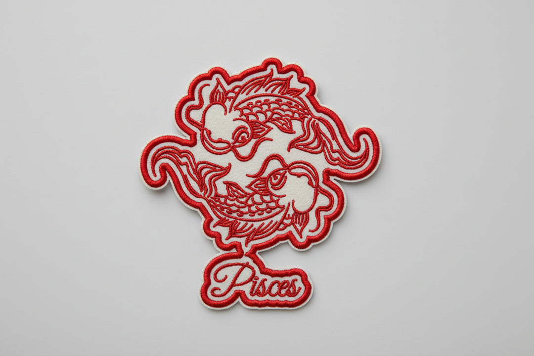 Red Pisces zodiac embroidered patch with two fish and “Pisces” script text on a white grid background.
