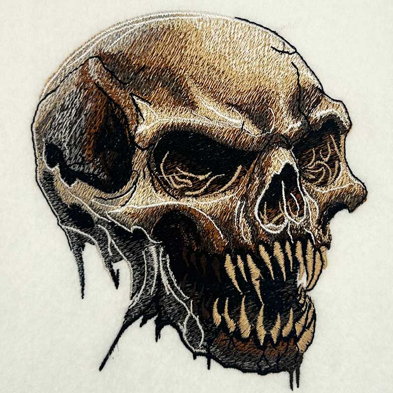 Feral Bonefang Skull Machine Embroidered Hoodie – Close-up detail of bone-toned fanged skull embroidery with fine crack and stitch texture | Hand Finished in Dubai
