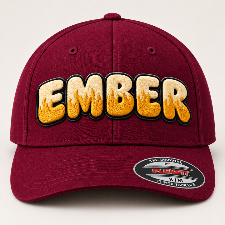 🔥🍷 Molten Silk – Inferno Pop Custom Cap Font · Cream fill · Gold flame · Black outline · Burgundy Flexfit | Hand Finished in Dubai | EmbroMania