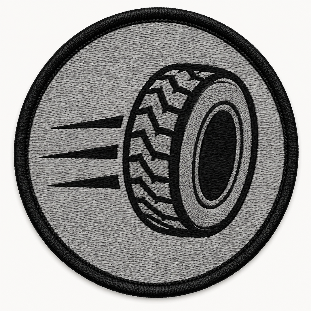 Speed Tire Track embroidery patch featuring a tire silhouette with motion lines trailing behind in flat black and grey | Hand Finished in Dubai | EmbroMania