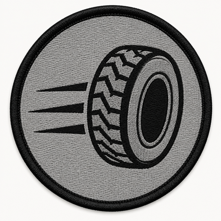 Speed Tire Track embroidery patch featuring a tire silhouette with motion lines trailing behind in flat black and grey | Hand Finished in Dubai | EmbroMania